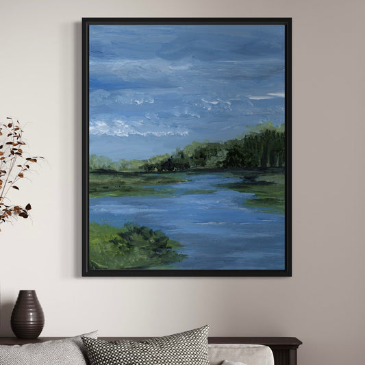 Framed painting of a landscape with water and trees on a wall above a sofa.
