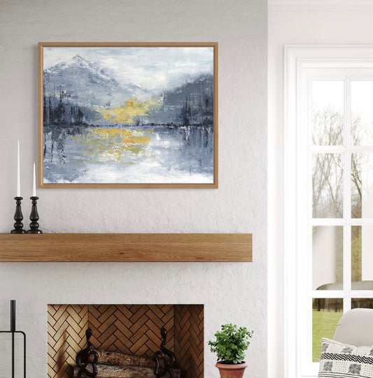 Framed abstract painting above a fireplace with candles and a plant.