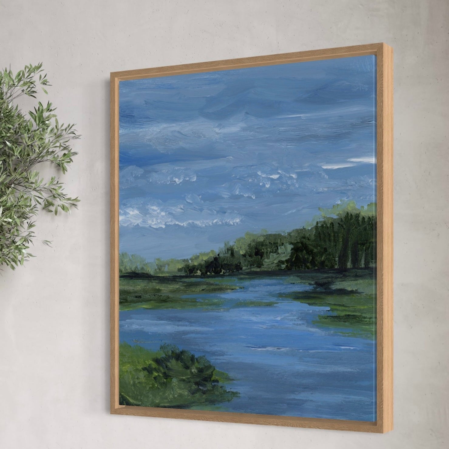 Framed painting of a landscape with a river and trees on a wall.