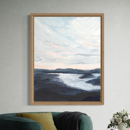 Framed artwork of a landscape with water and sky on a wall above a green sofa.