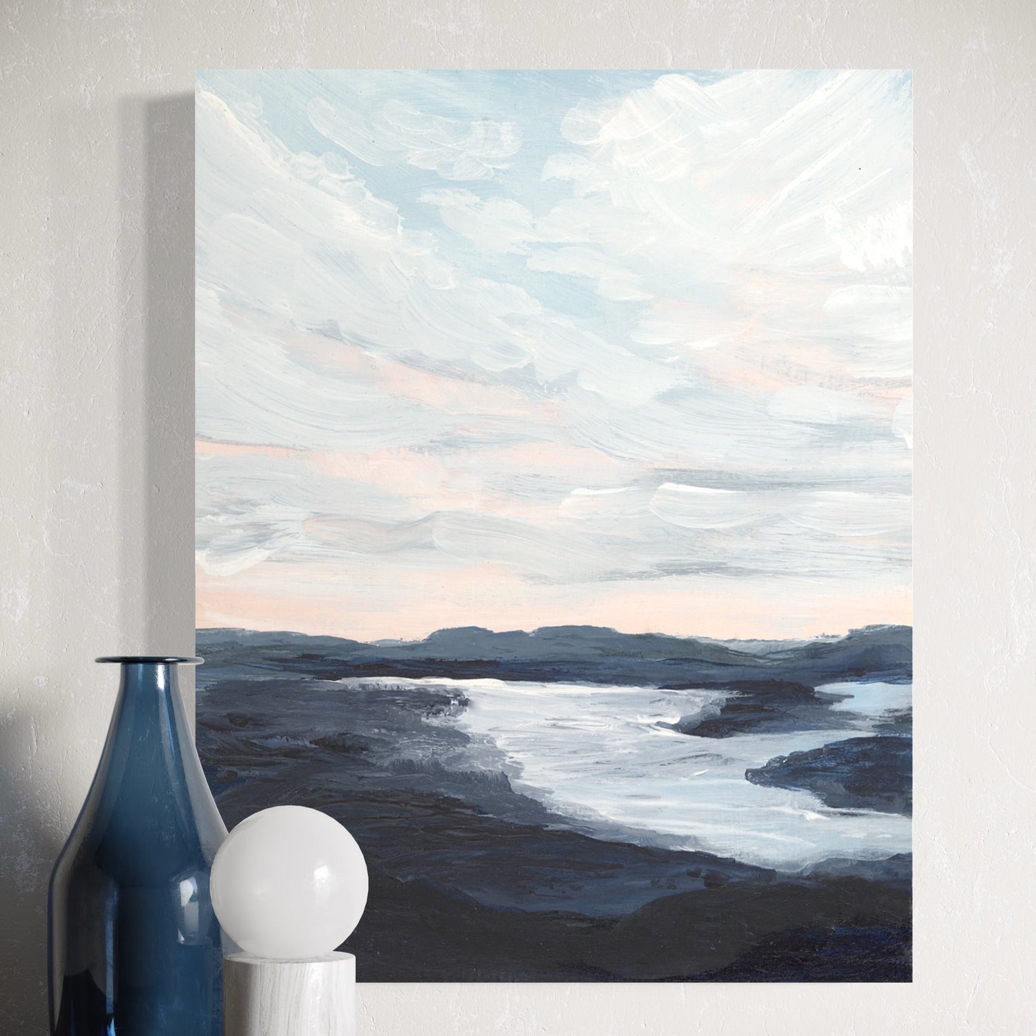 Painting of a landscape with mountains and water on a wall above a wooden shelf with decorative items.