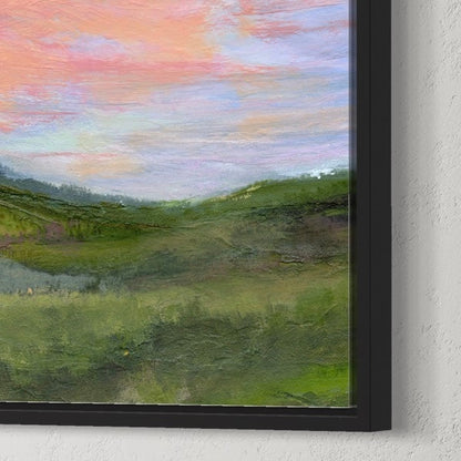 Framed painting of a landscape with green fields and a colorful sky.
