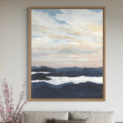 Framed abstract artwork of clouds and mountains on a wall above a sofa.