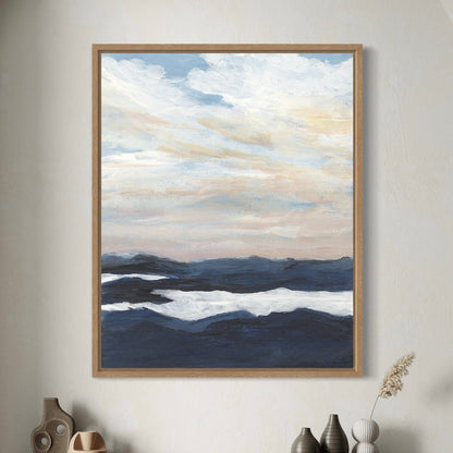Framed abstract artwork of a landscape with blue and white tones on a wall above a wooden console table.