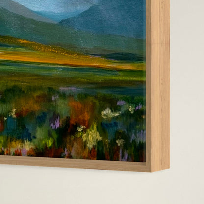 Framed painting of a landscape with fields and mountains