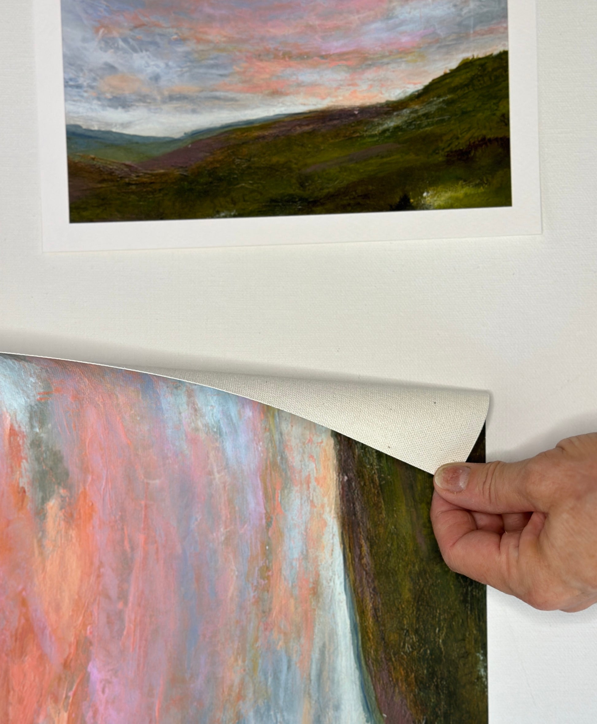 Person peeling back a protective layer on a framed landscape painting.