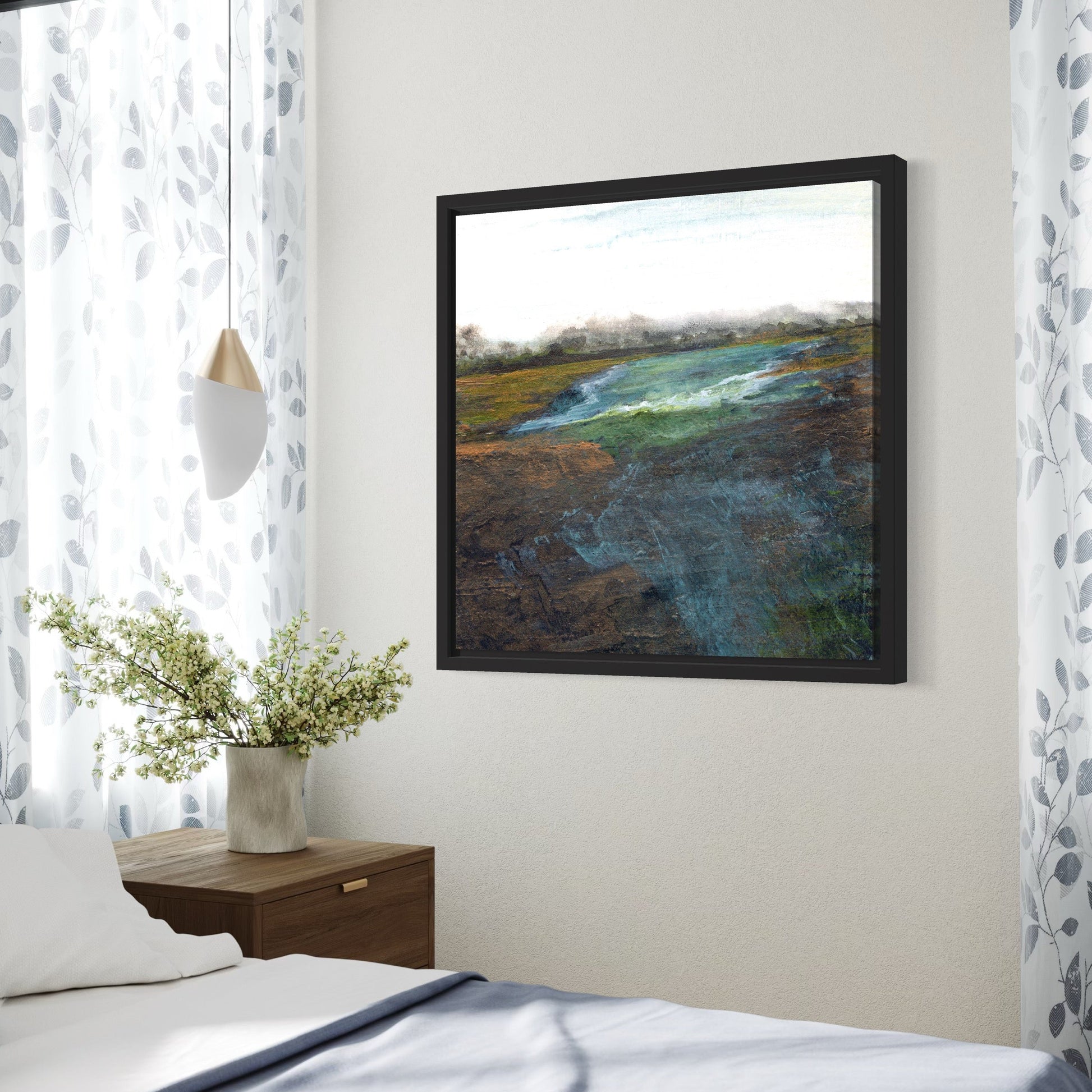 Framed abstract painting on a wall above a bed with a side table and plant.