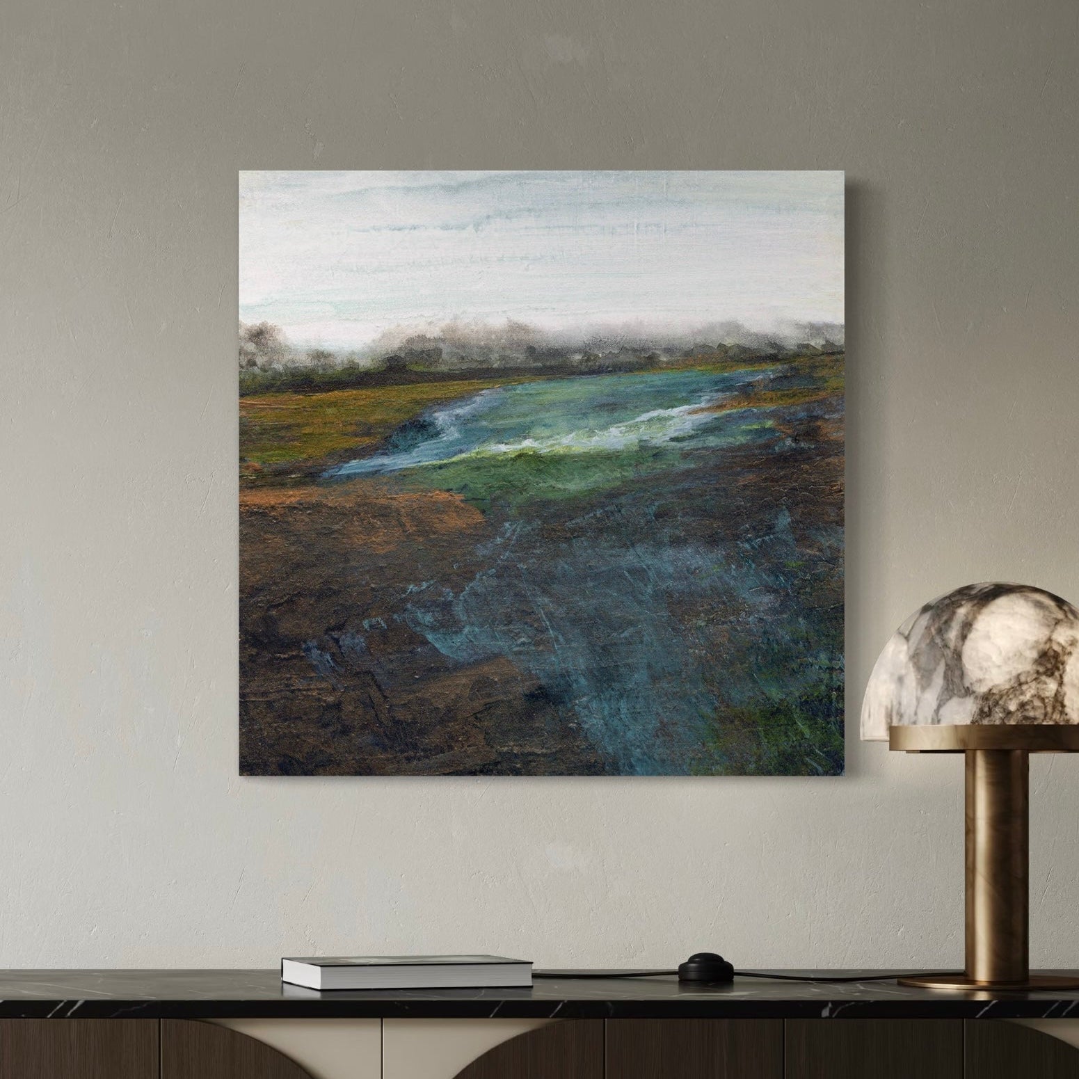 Abstract landscape painting on a wall above a console table with a lamp.