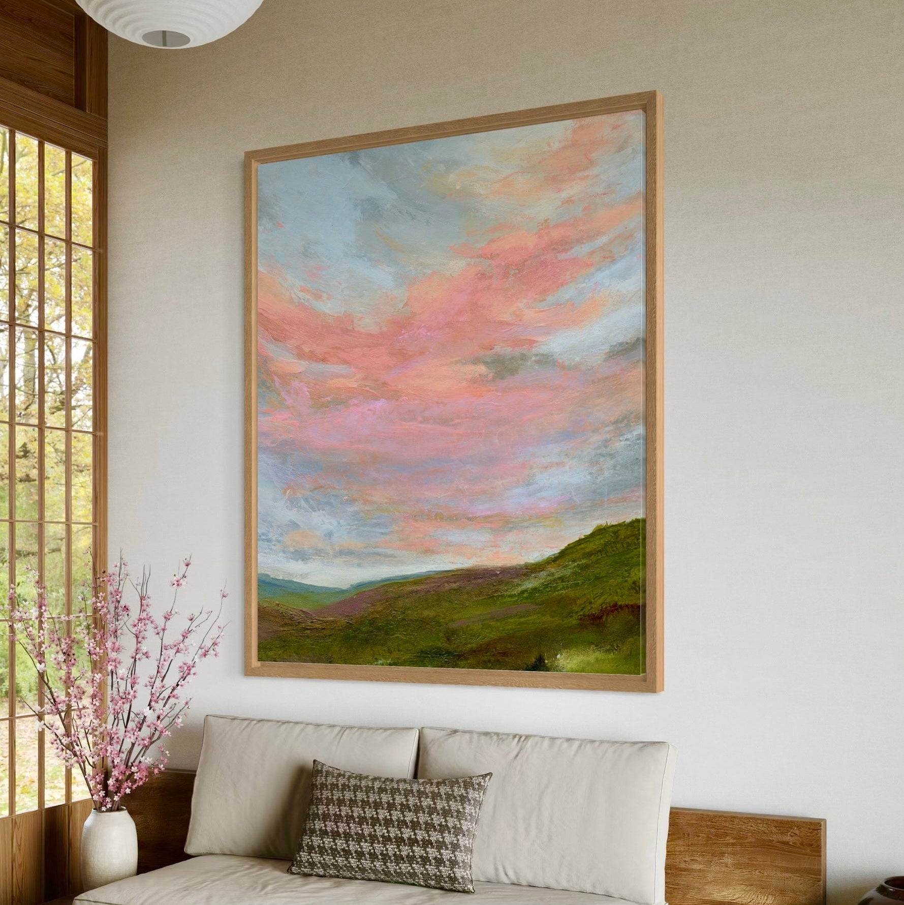 Framed landscape painting on a wall above a sofa with decorative pillows.