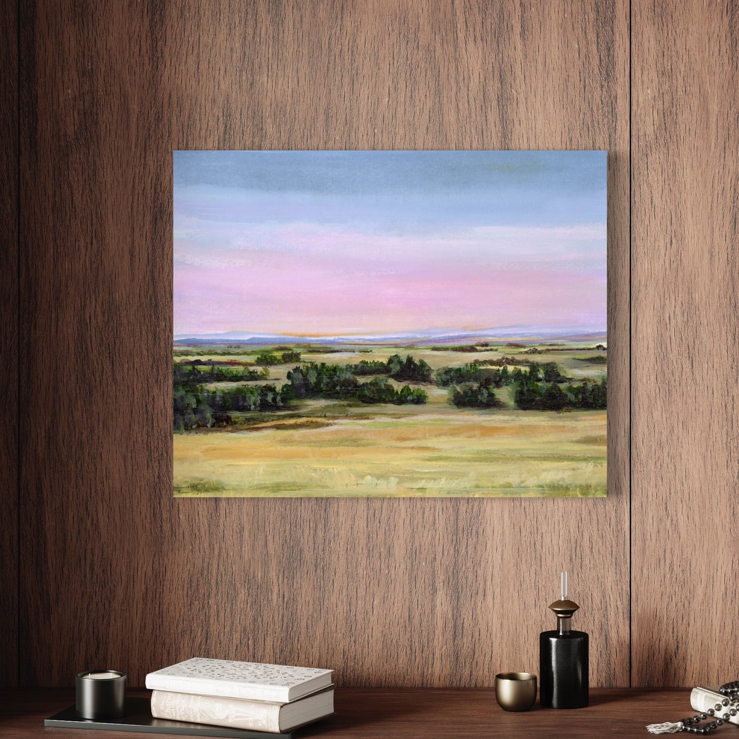 Framed landscape painting on a wooden wall with decor items below.