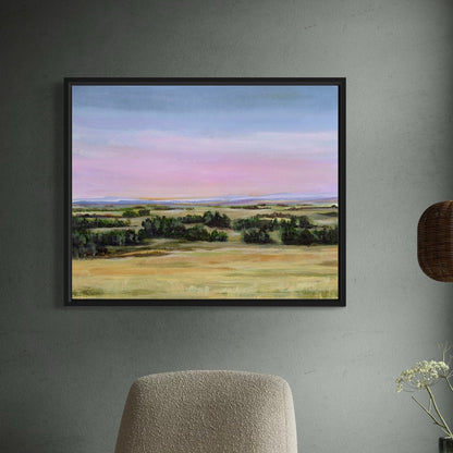 Framed landscape painting on a wall with a chair and plant in the foreground