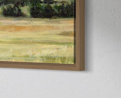 Framed painting of a landscape with green and brown tones on a white wall.