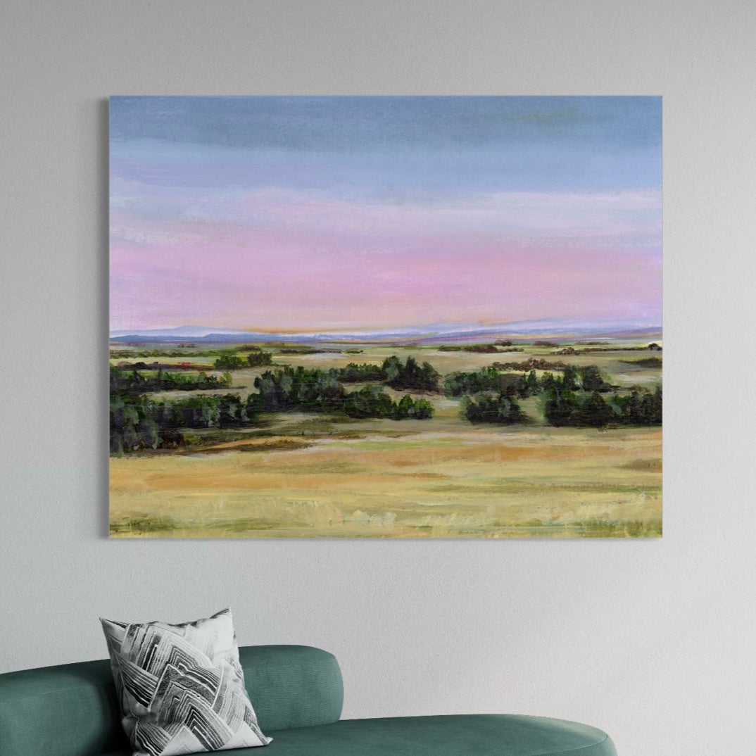 Painting of a landscape with fields and trees on a wall above a green sofa.