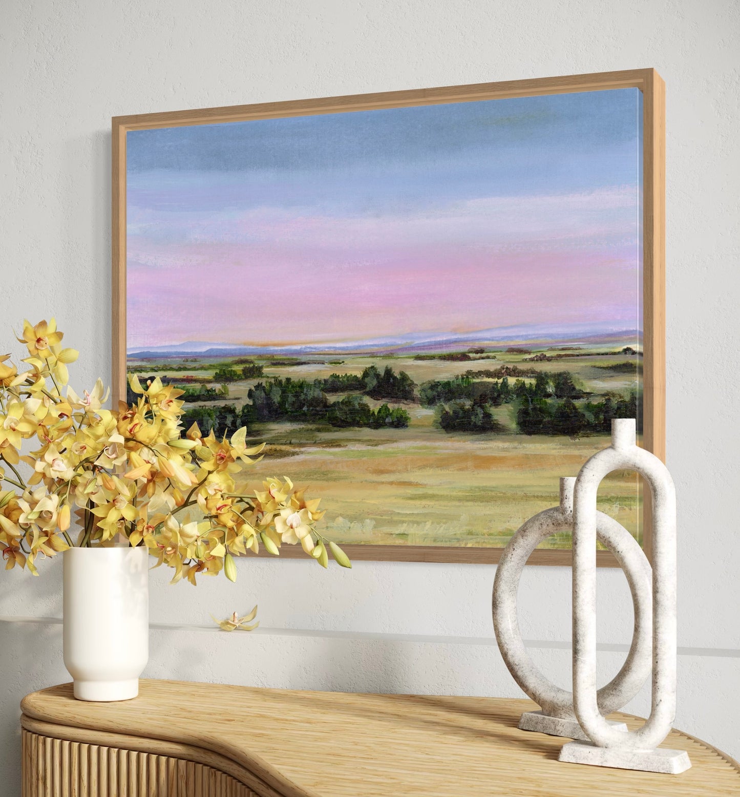 Framed landscape painting on a wall with decorative items below