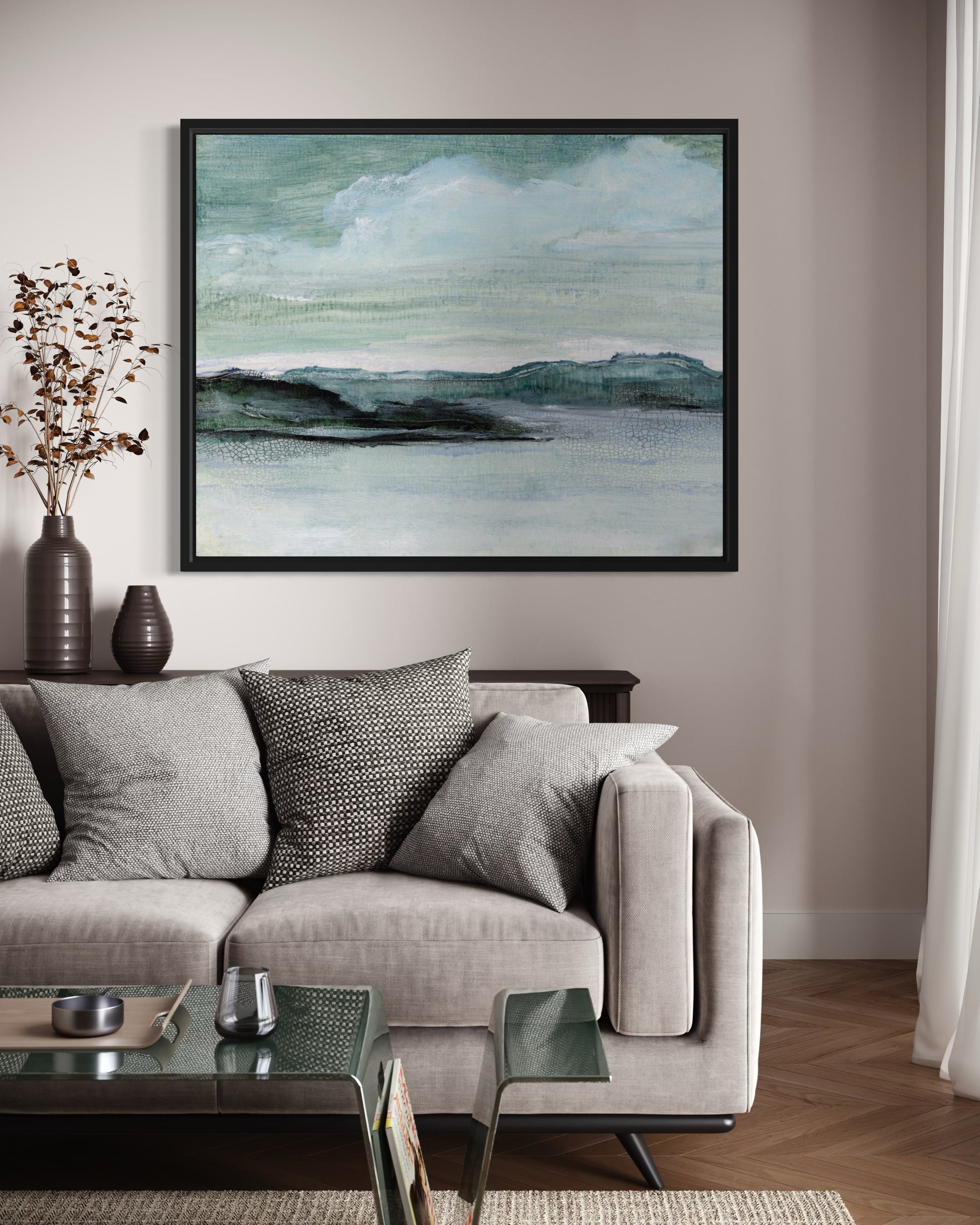 Living room with a gray sofa, glass coffee table, and framed abstract artwork on the wall.