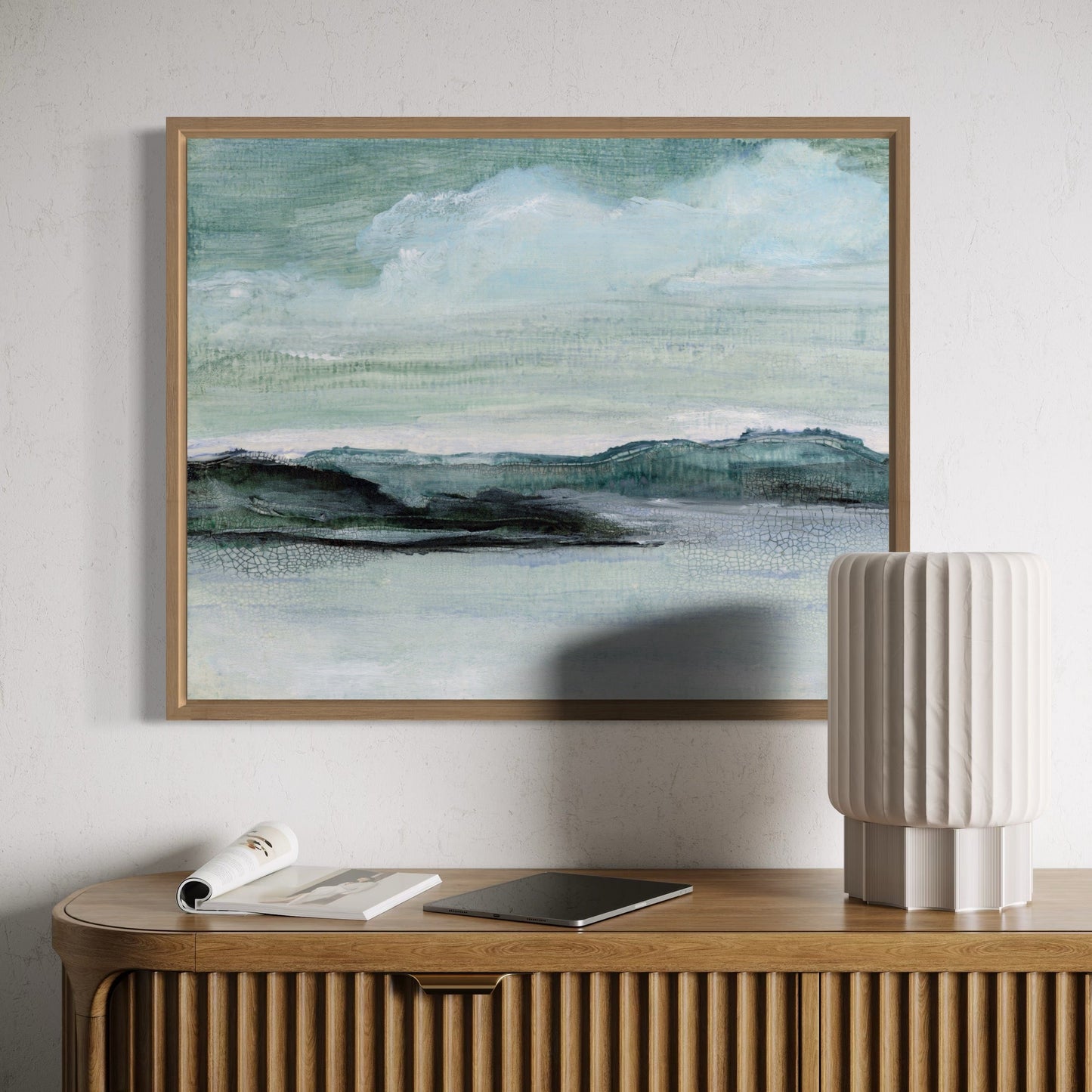 Framed landscape painting on a wall above a wooden console table with decorative items.