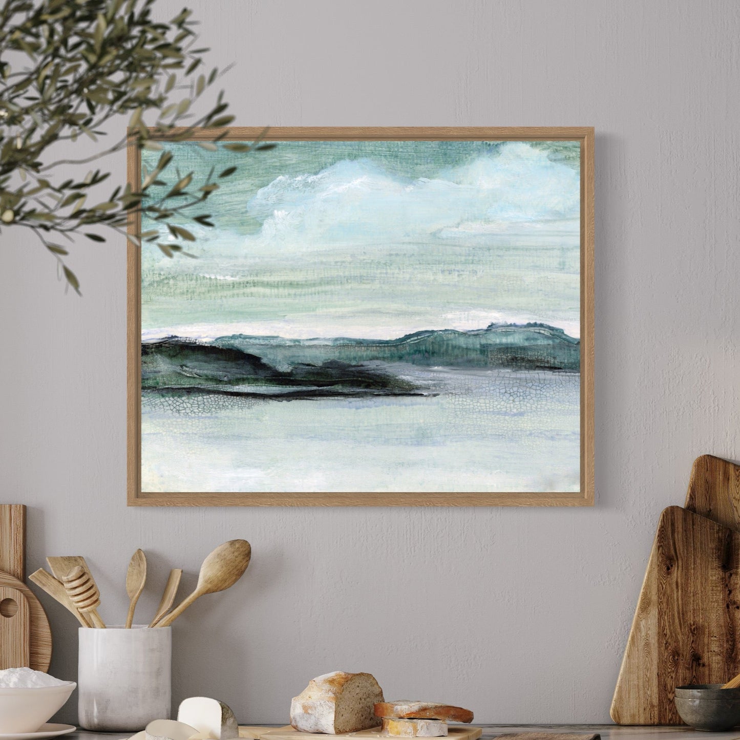 Kitchen counter with wooden cutting boards, ceramic items, and a framed landscape painting on a gray wall.