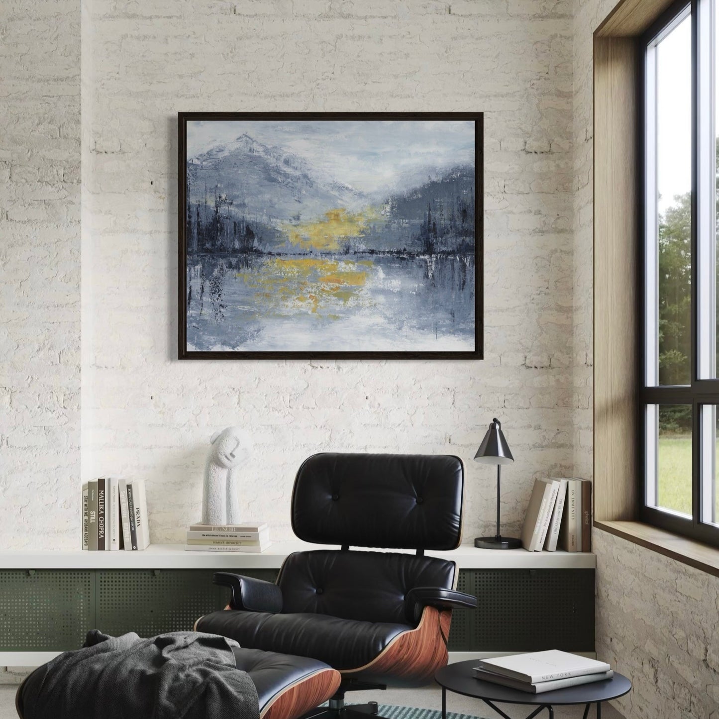 Modern interior with a black chair, table, and abstract painting on a white brick wall.